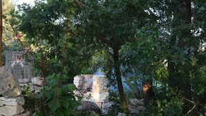 Un jardín con muro de piedra, un árbol y una pequeña cascada.