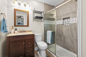 Ein Badezimmer mit Dusche, Toilette, Waschtisch und Spiegel.