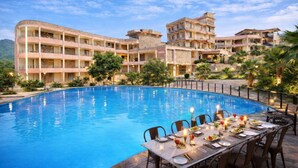 A hotel with a swimming pool, outdoor dining area, and multiple buildings with balconies. - OPO Palm Villa Dritan (Udaipur)