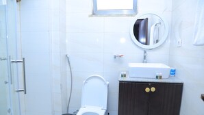 A bathroom with a toilet, a sink, a mirror, and a cabinet. - yellow apple hotel (Addis Ababa)