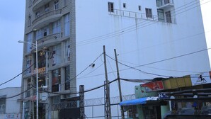 A multi-story building with a prominent 'Yellow Apple Hotel' sign, multiple balconies, and a large billboard on the side. - yellow apple hotel (Addis Ababa)