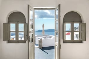 An open doorway leading to a balcony with a view of the sea and a white umbrella. - Chess House - Santorini Traditional Home (Santorini)