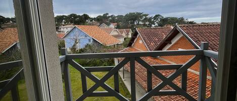 A balcony with a view of neighboring houses and a cloudy sky.