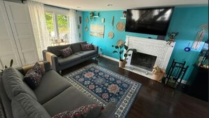 A living room with a sofa, a TV, a fireplace, and a blue wall.