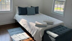 A bedroom with a bed, a bench, and a painting on the wall.