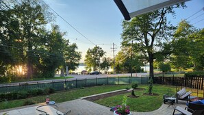A patio with outdoor furniture, a garden, and a view of a road and trees.