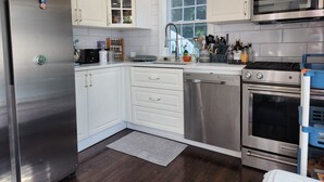 A modern kitchen with stainless steel appliances, white cabinetry, and a window providing natural light.