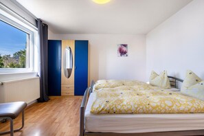 Hotellihuone, jossa on sänky, työpöytä, ikkuna verhoilla, patteri ja seinälle kiinnitetty peili.
