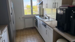 Una cocina con ventana, refrigerador, lavavajillas y cafetera.