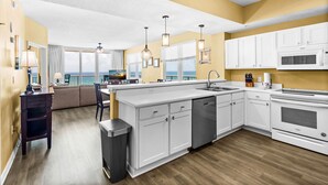 A modern kitchen with white cabinetry, a built-in dishwasher, and a large island. - 🌴🩴Gulf-Front 3BR | Steps to Navarre Beach Pier | Summerwind Center 504 (Navarre Beach)