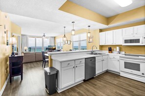 A modern kitchen with white cabinetry, a built-in dishwasher, and a large island. - 🌴🩴Gulf-Front 3BR | Steps to Navarre Beach Pier | Summerwind Center 504 (Navarre Beach)