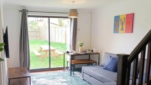 En stue med en sofa, et spisebord, en stueplante og en skydedør til en patio.