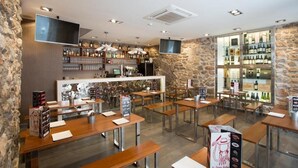 A restaurant with stone walls, wooden tables, and a bar area with shelves of bottles. - La sepia Boba (Peñíscola)