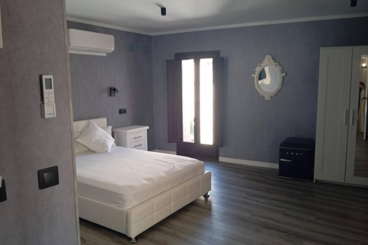 A bedroom with a bed, bedside tables, a wardrobe, a mirror, and a window.