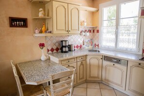 A kitchen with a granite countertop, a sink, a dishwasher, and a dining area with a table and chairs.