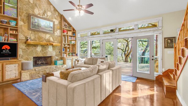 A spacious living room with a stone fireplace, a large sectional sofa, and a television. - Private 14 Acres | Pool, Pickleball, Hot Tub & Guest House with Views (Wimberley)