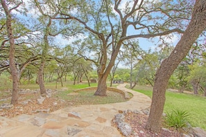 A landscaped garden with stone pathways, trees, and a circular seating area.