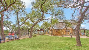 A house with a stone exterior, a fenced yard, and a gazebo. - Private 14 Acres | Pool, Pickleball, Hot Tub & Guest House with Views (Wimberley)