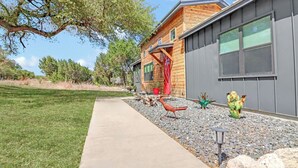 Ett modernt hus med en gångbana av betong, en träfasad och en kaktusträdgård.