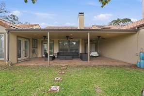 A covered patio with a seating area, a chimney, and a hose connected to the house.