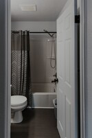 Bañera con ducha, toallas, jabón, papel higiénico