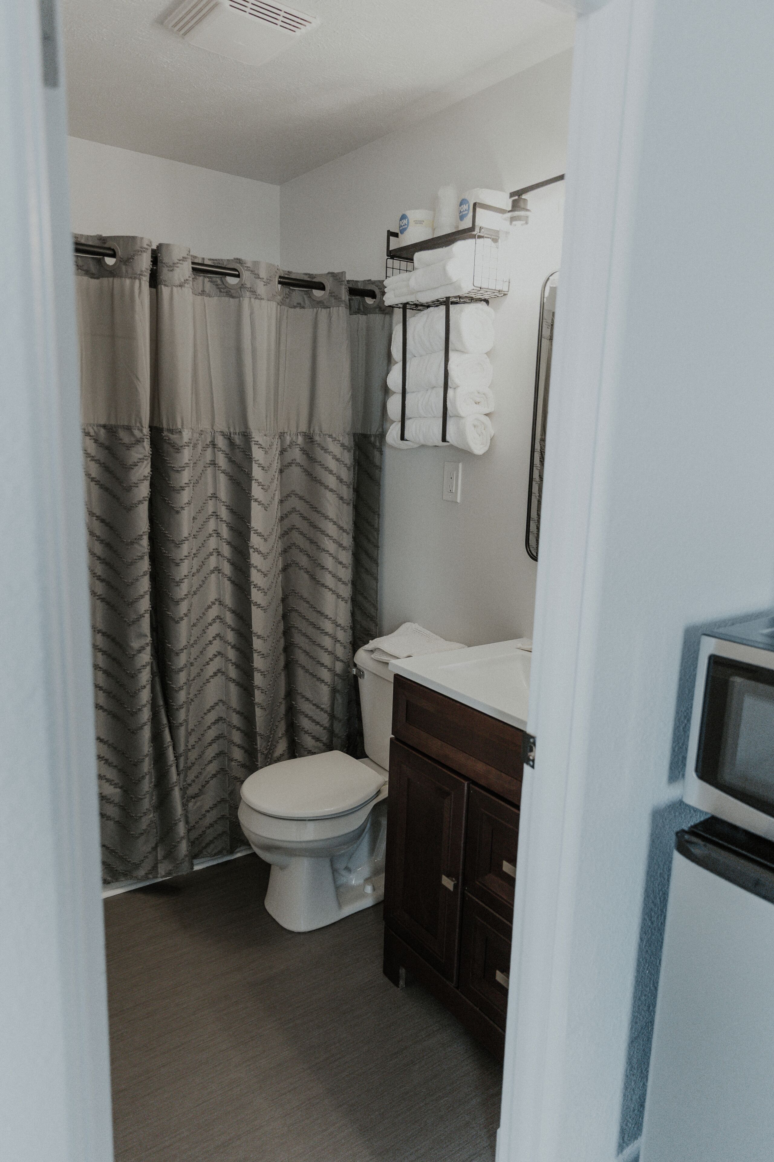 A bathroom with a toilet, a shower curtain, a towel rack, and a sink.