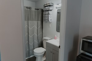 Un baño con cortina de ducha, inodoro, lavamanos y espejo.