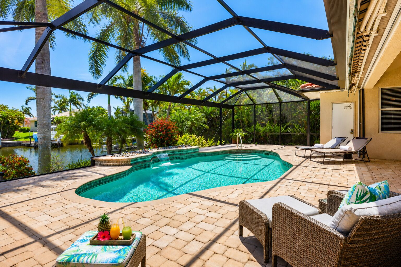 A covered outdoor swimming pool with lounge chairs and a table with drinks.