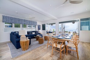 A modern living room with a sofa, coffee table, and dining area with chairs. - Sea Breeze House 4 Bedroom Villa (Prospect)