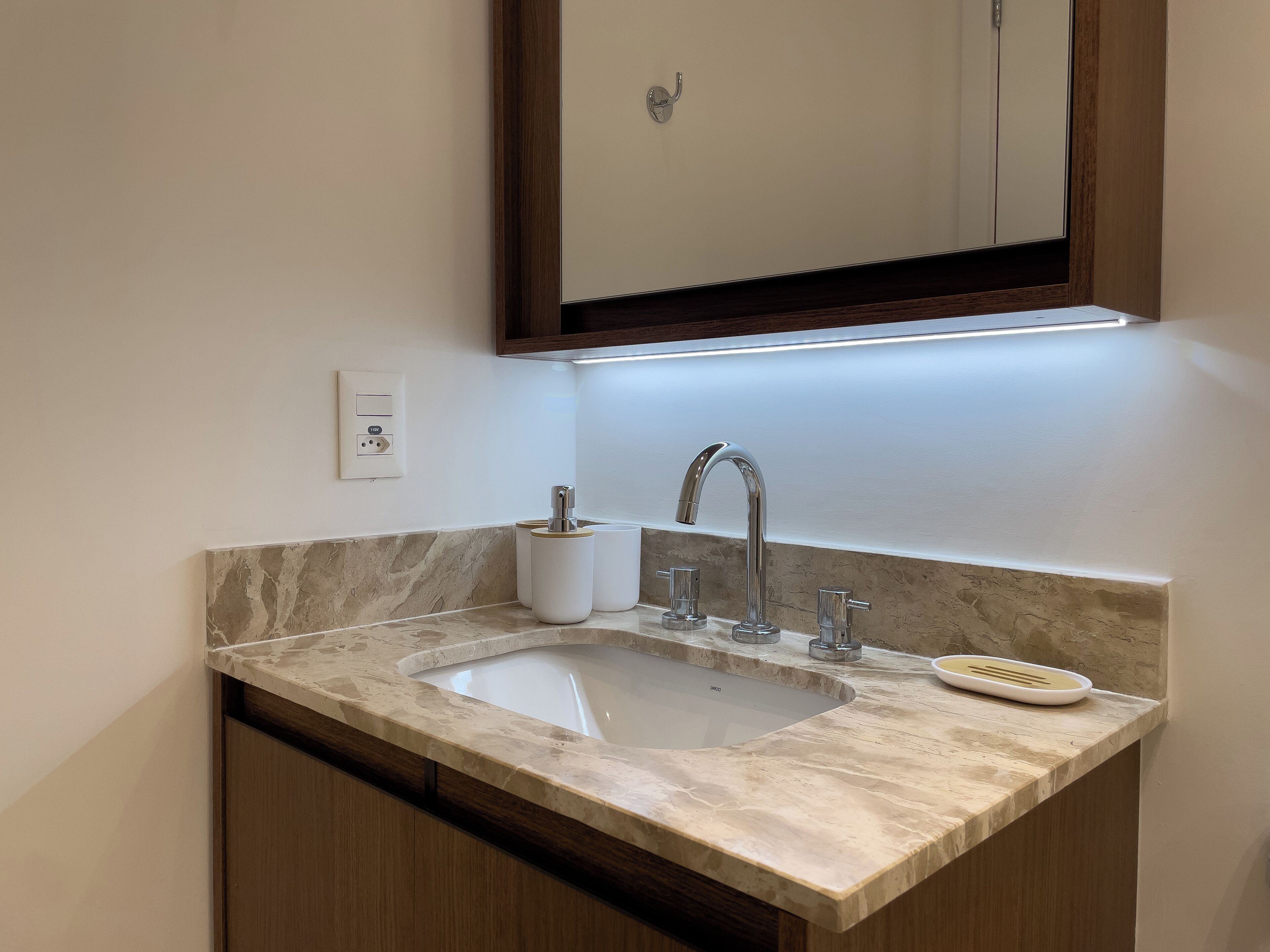 Un baño con lavamanos de mármol, un espejo y un perchero para toallas.