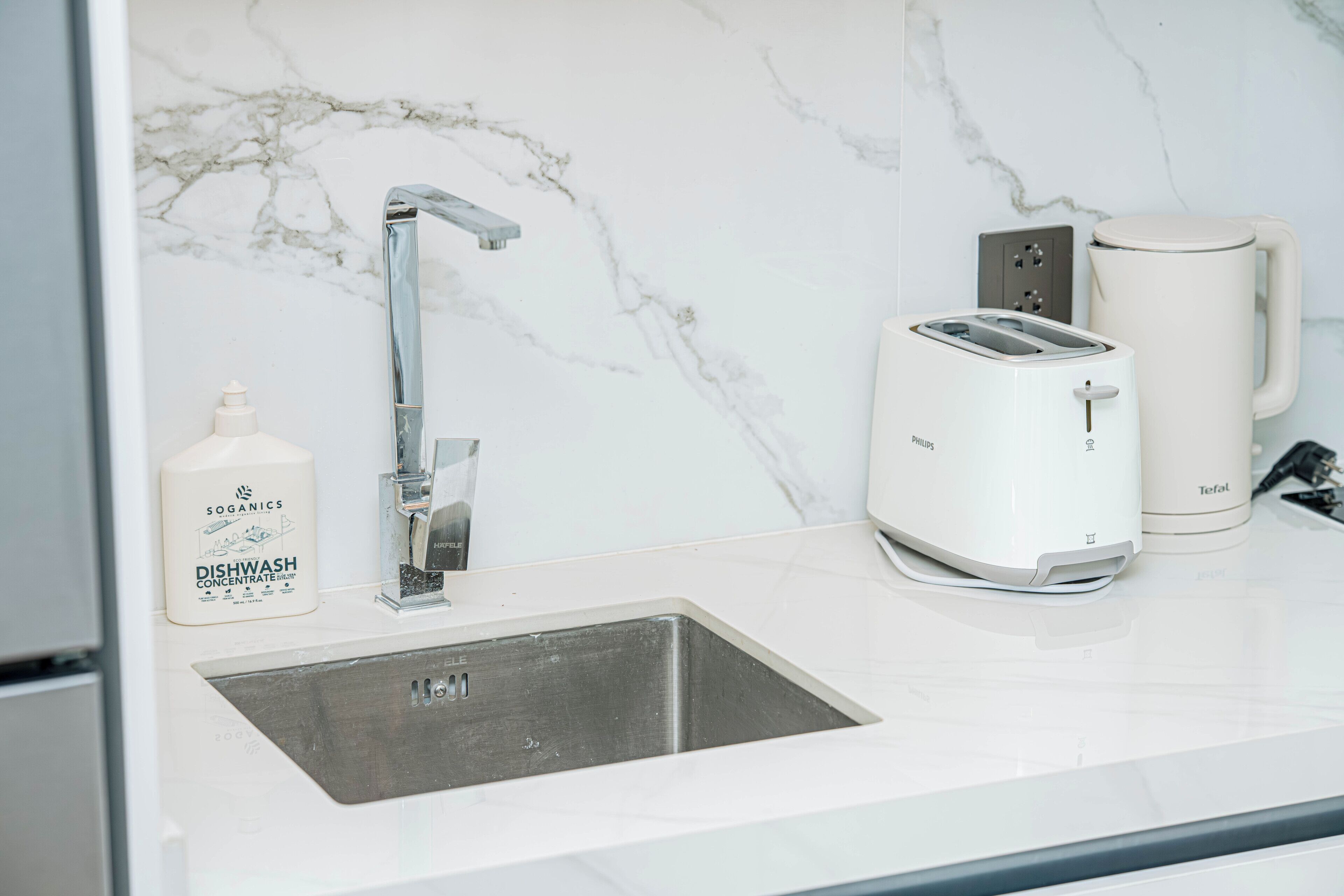 A kitchen with a sink, a toaster, a coffee maker, and a dishwash detergent bottle.
