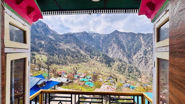 A mountain view from a room with a balcony, featuring a wooden railing and a green ceiling. - Dolma homestay by Orko (Nichar)