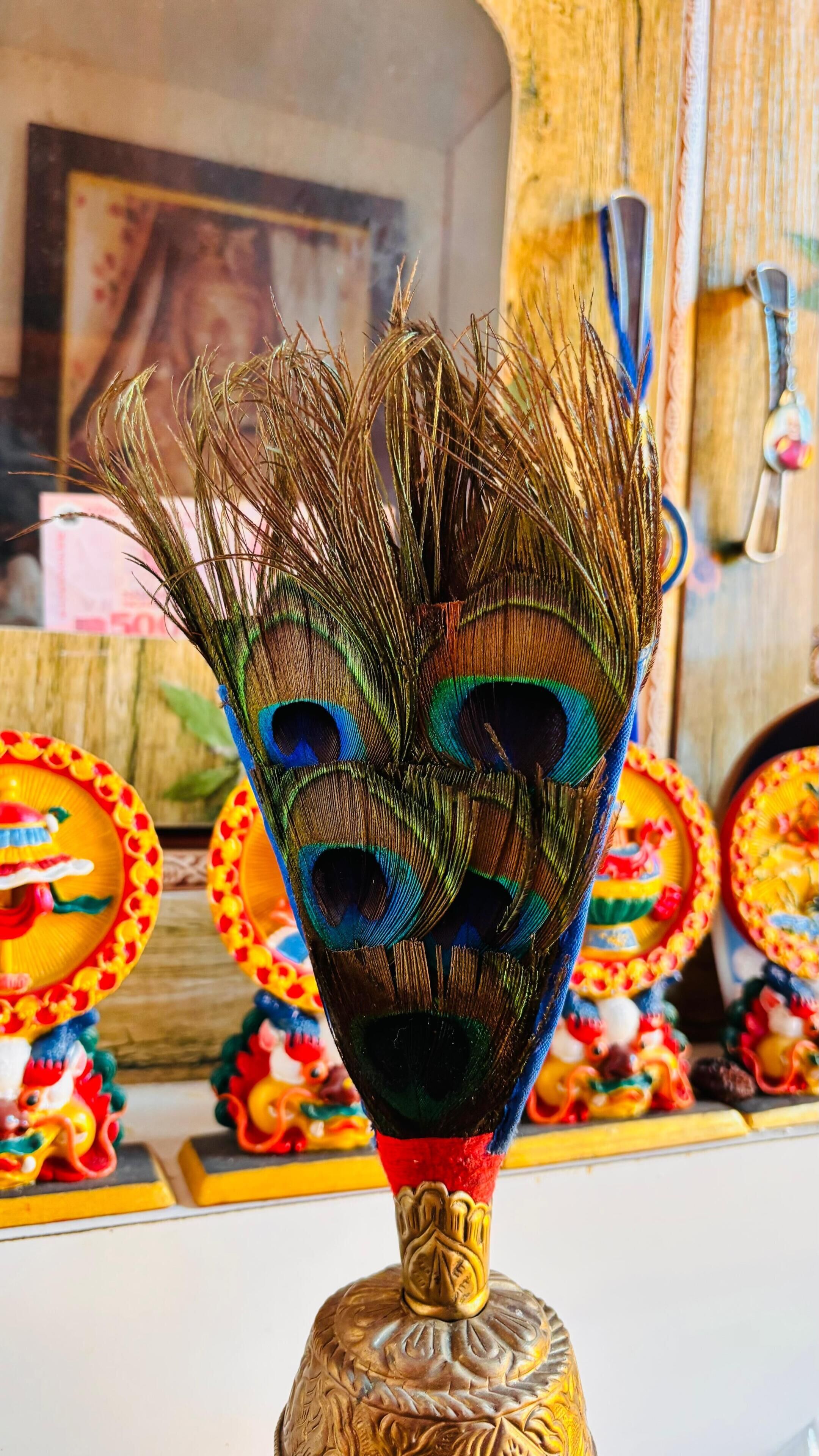 Une plume de paon dans un vase en verre décoratif, posé sur un support en bois.