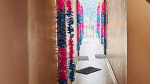 A hallway with a wooden ceiling and walls, leading to a room with a patterned floor. - Dolma homestay by Orko (Nichar)