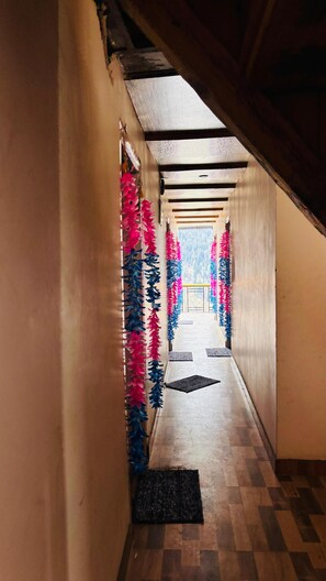 A hallway with a wooden ceiling and walls, leading to a room with a patterned floor.