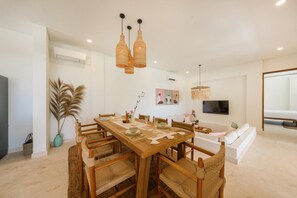 A dining area with a wooden table, wicker chairs, and hanging wicker lamps. - Villa Svara - 4BR Villa w/ Panoramic Ocean Views (Purwakerti)