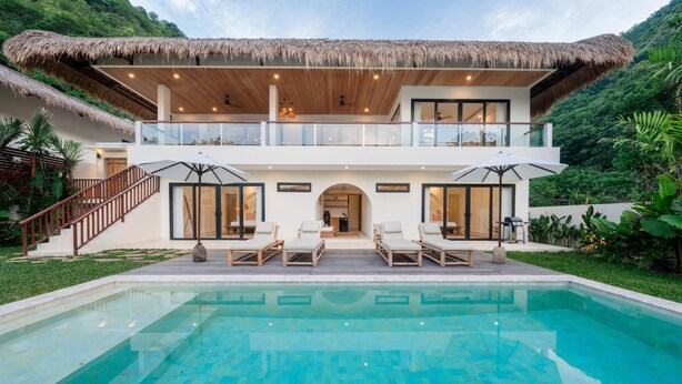 A two-story house with a pool, a thatched roof, and a balcony overlooking the greenery. - Villa Svara - 4BR Villa w/ Panoramic Ocean Views (Purwakerti)