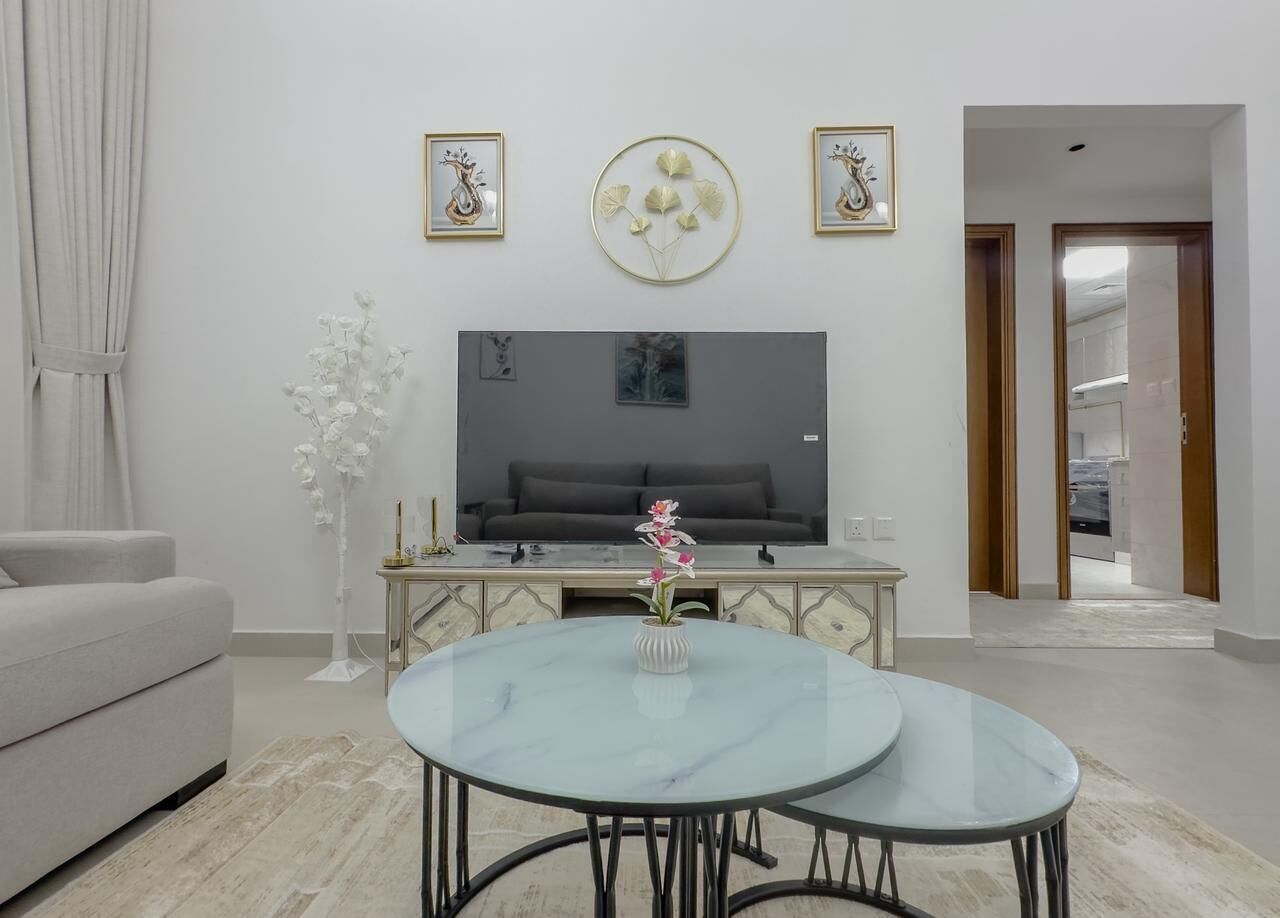 Una sala de estar con un sofá, televisión, mesa de centro y decoración mural.