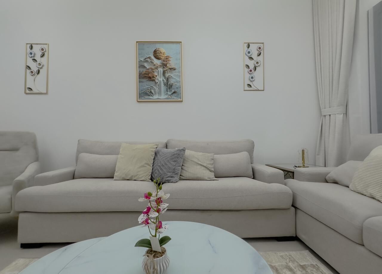 A modern living room with a sofa, a coffee table, and two framed artworks on the wall.
