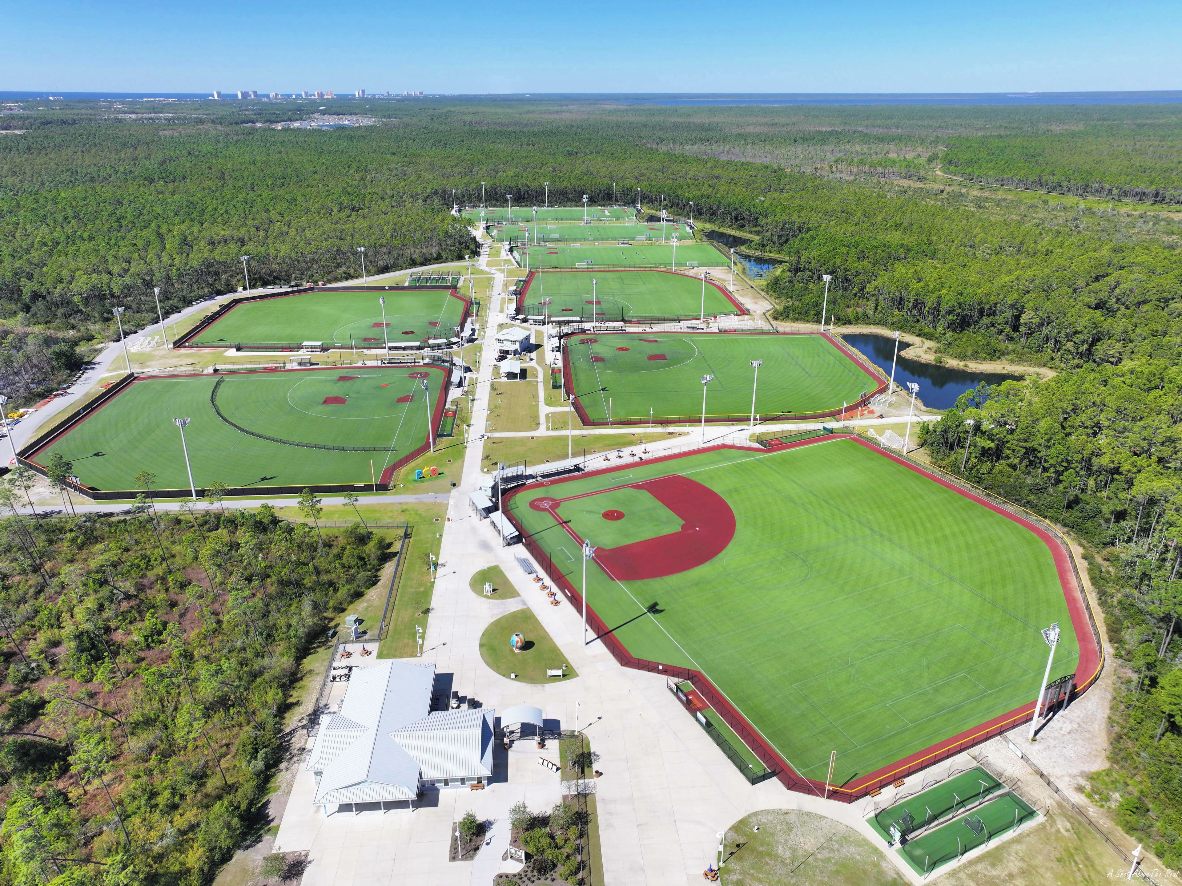 An aerial view of a sports complex with multiple fields and a large building.