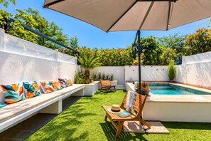 A backyard with a pool, a seating area with colorful cushions, and a wooden chair. - Villa Cocoon—Private Pool—Near the Ocean & Montpellier (Mauguio)