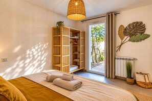 A bedroom with a bed, a wooden wardrobe, a radiator, and a view of the outdoors. - Villa Cocoon—Private Pool—Near the Ocean & Montpellier (Mauguio)