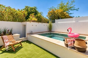 A private pool area with a wooden chair, a flamingo float, and a small table with a lamp. - Villa Cocoon—Private Pool—Near the Ocean & Montpellier (Mauguio)