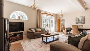 Ein Wohnzimmer mit Fernseher, Sofa, Couchtisch und einem großen Fenster.