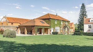 Ein großes, mehrgeschossiges Haus mit Backsteinfassade, einem Ziegeldach und einem gepflegten Rasen.