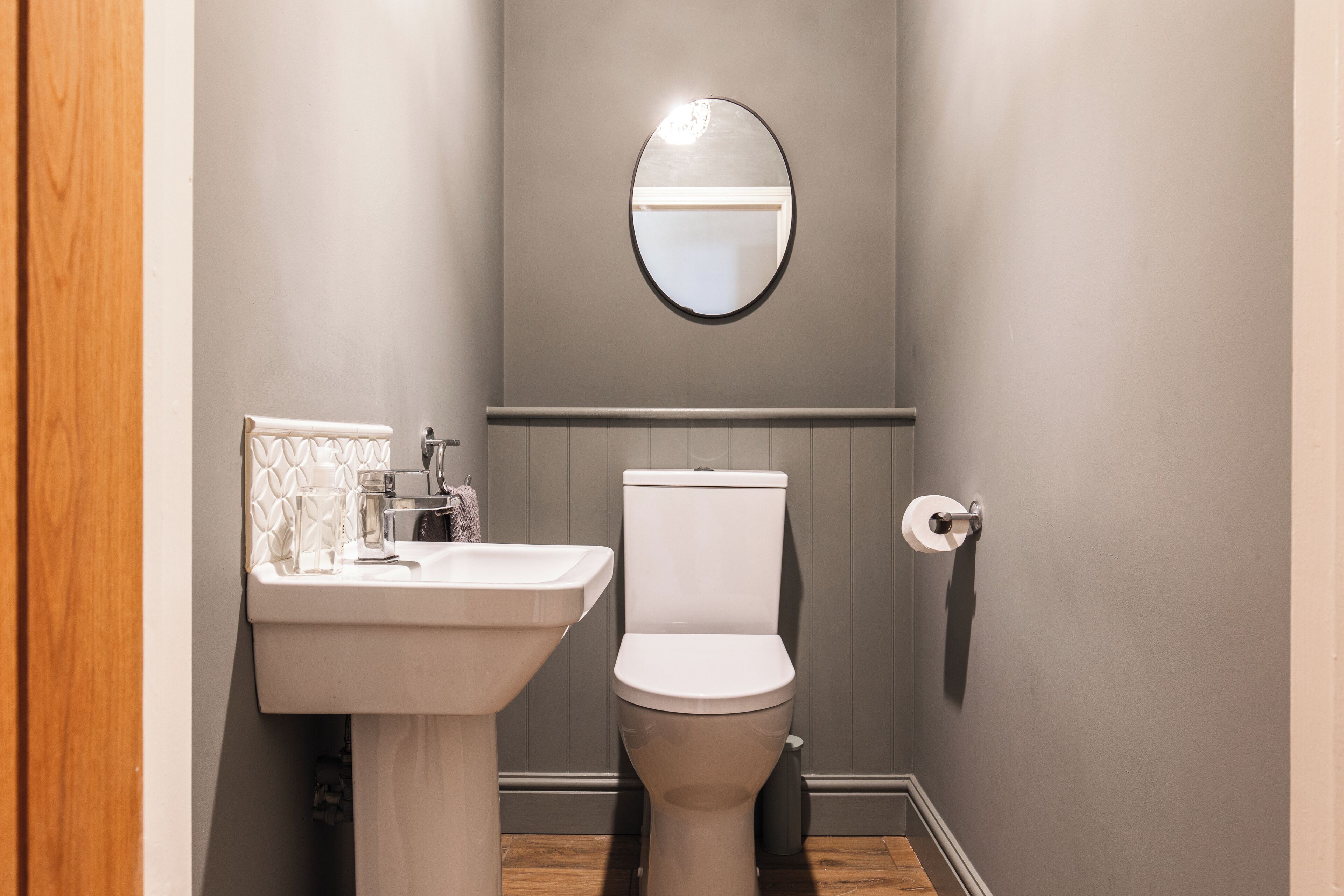 A bathroom with a sink, toilet, and a mirror on the wall.