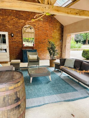 A cozy room with a brick wall, a wooden ceiling, a glass table, a sofa, and a large barrel. - The Coach House | Sleeps 6 | Ideal Norfolk Touring Base - friends, family & work (Wymondham)