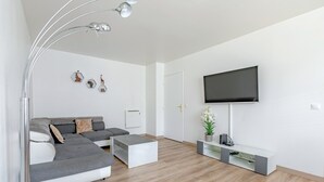 Una sala de estar moderna con un sofá modular, una mesa de centro, un televisor de pantalla plana y una decoración minimalista.