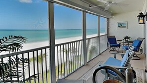 Ein Balkon mit Blick auf den Strand, einem Deckenventilator und blauen Stühlen.