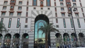 Et hotel med stor buet indgang, mange vinduer og et skilt, der angiver, at det er 'Suliman Al Taiba Hotel'.